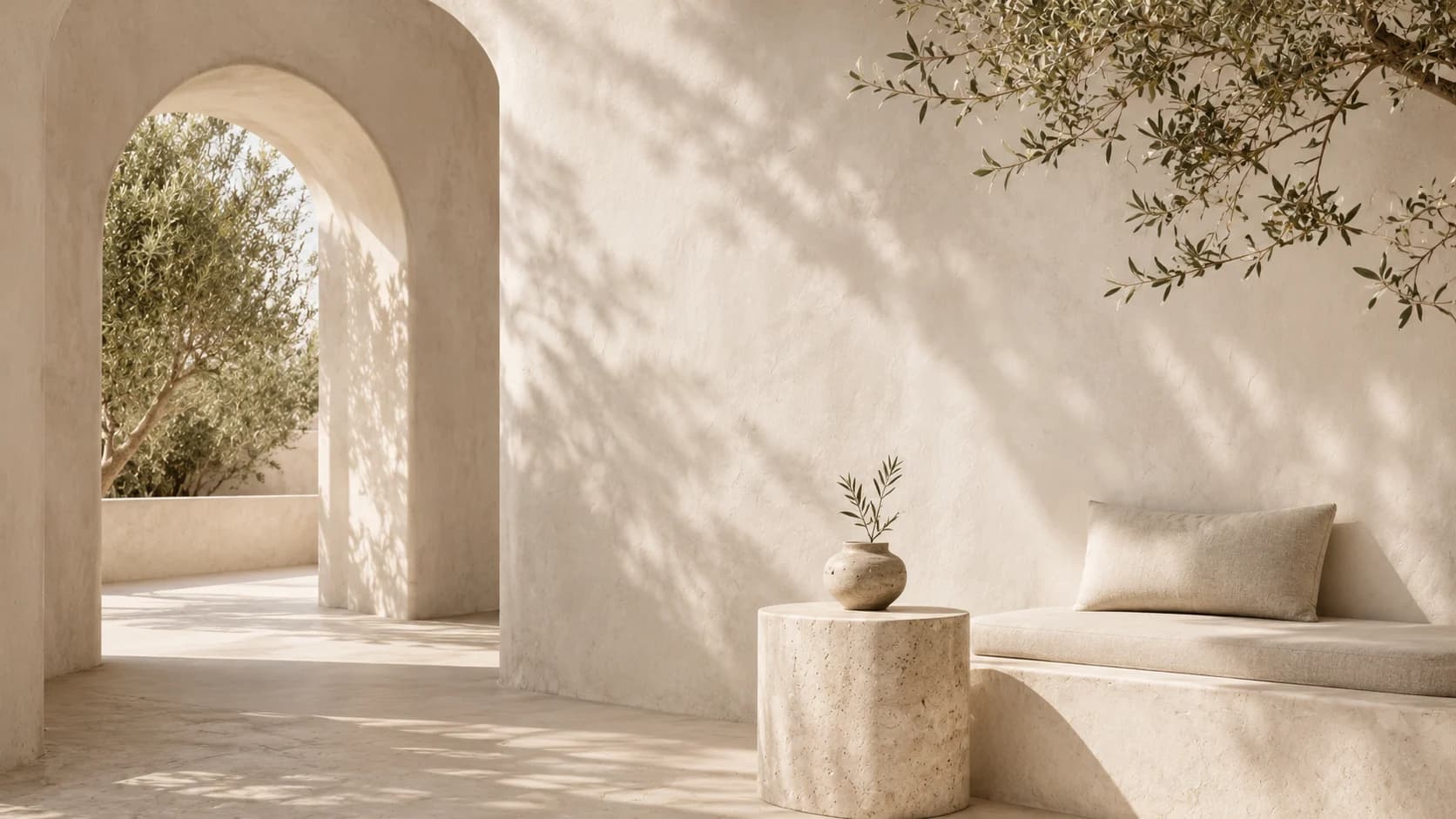 An arched Mediterranean patio with warm stone, soft seating, and coastal light.
