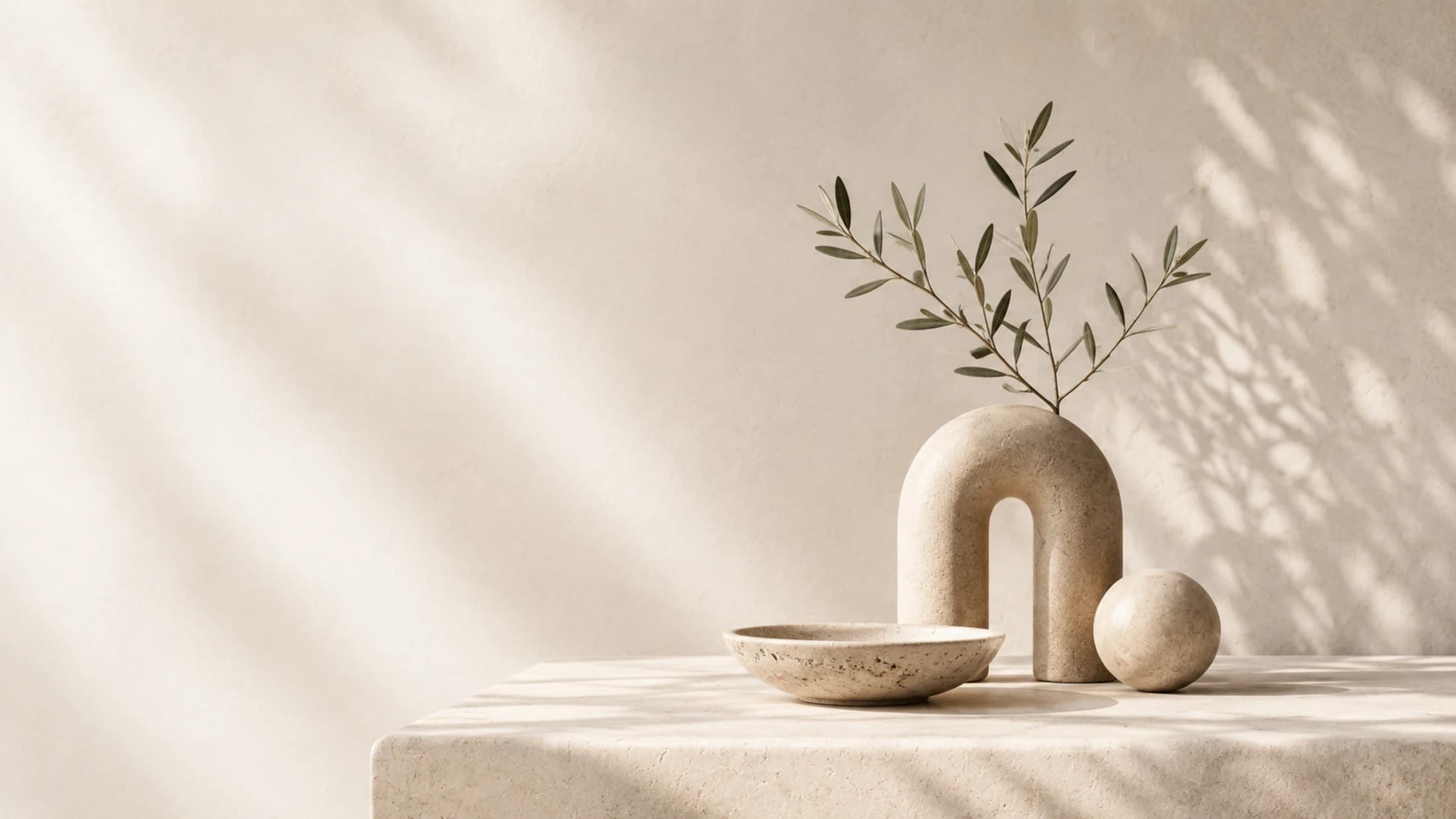 A ceramic vase and bowl on a warm stone tabletop.